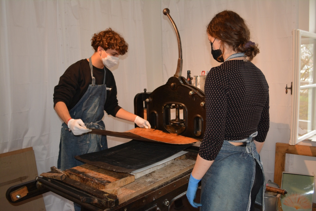 Zwei Jugendliche beim Lithographie-Druck an der Druckerpresse im Herkomer Museum